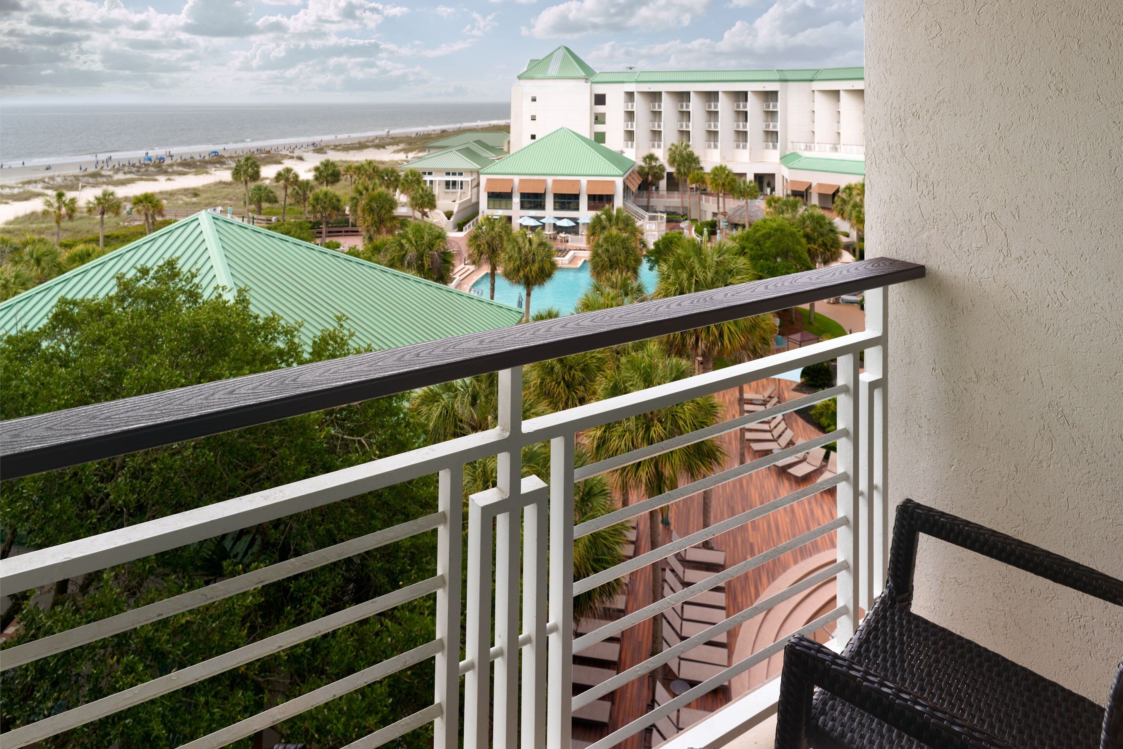 A hotel with a pool, palm trees, and a view of the beach.