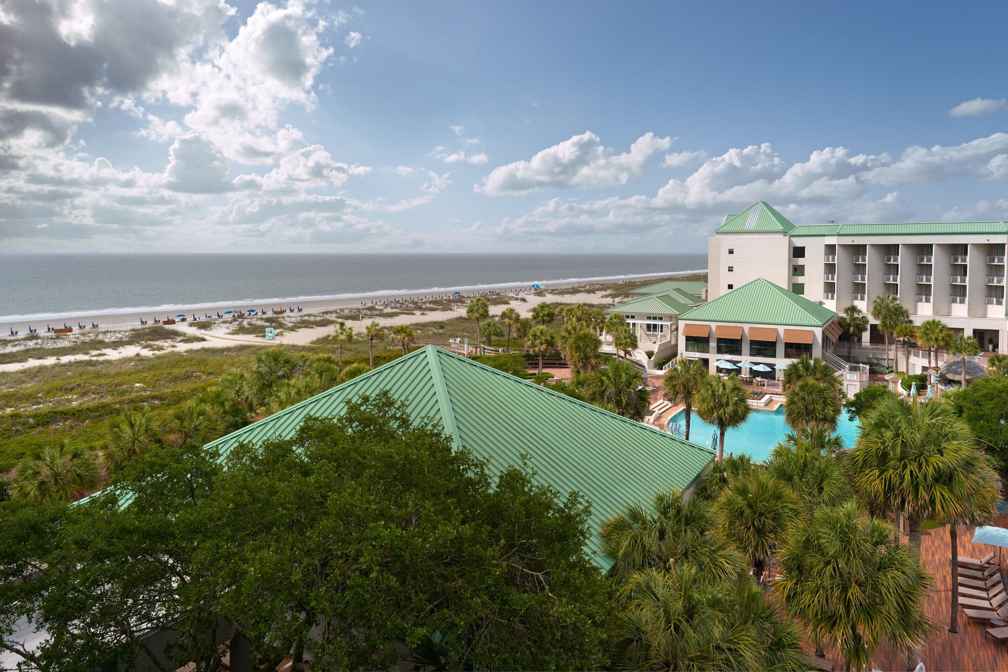 A resort with a pool, beachfront view, and multiple buildings with green roofs.