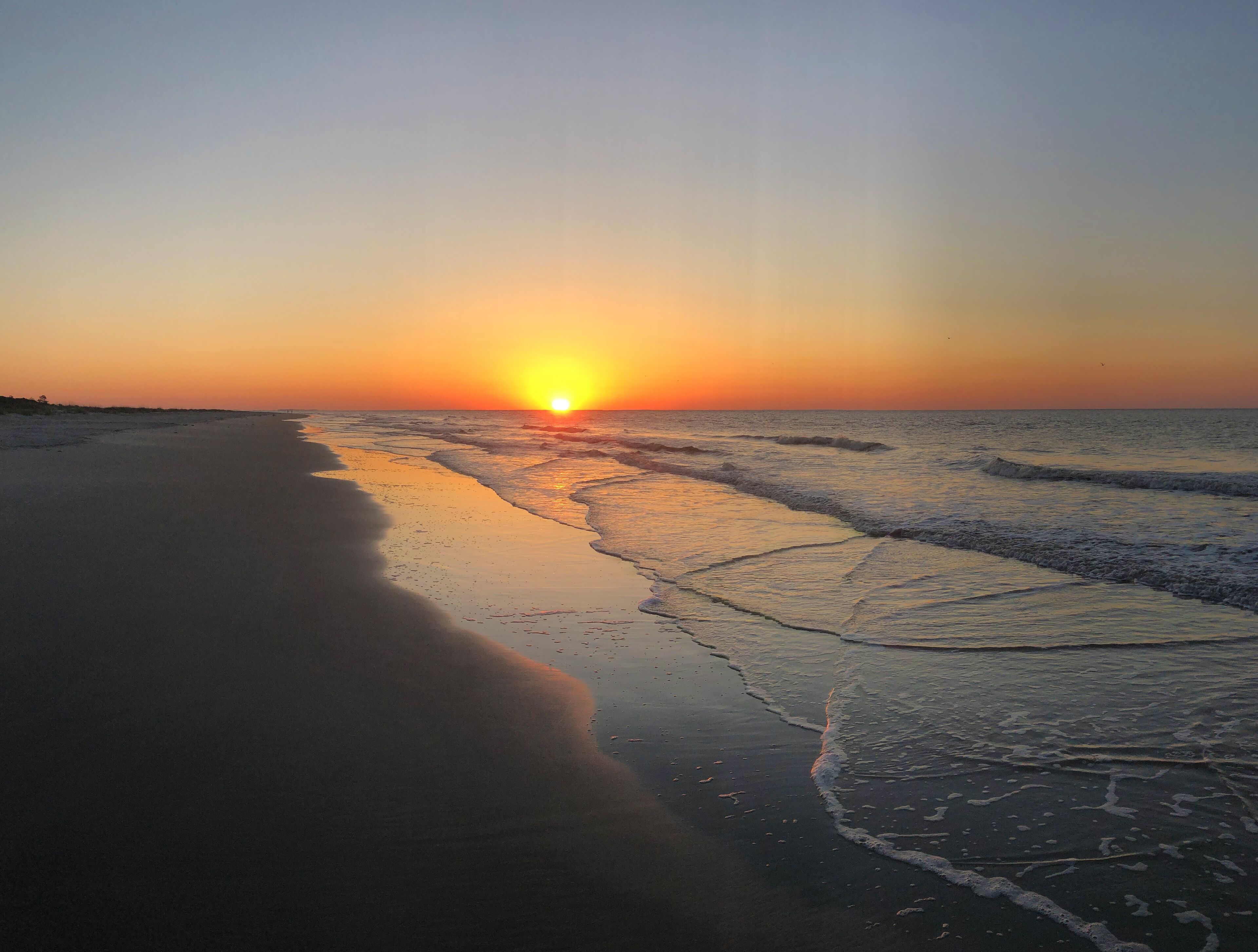 A beach at sunset with waves gently lapping the shore.
