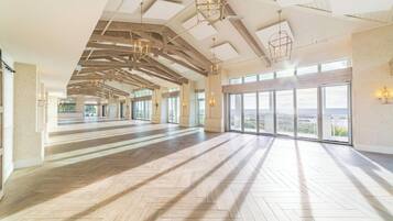 A spacious interior with a high ceiling, large windows, and a wooden floor.