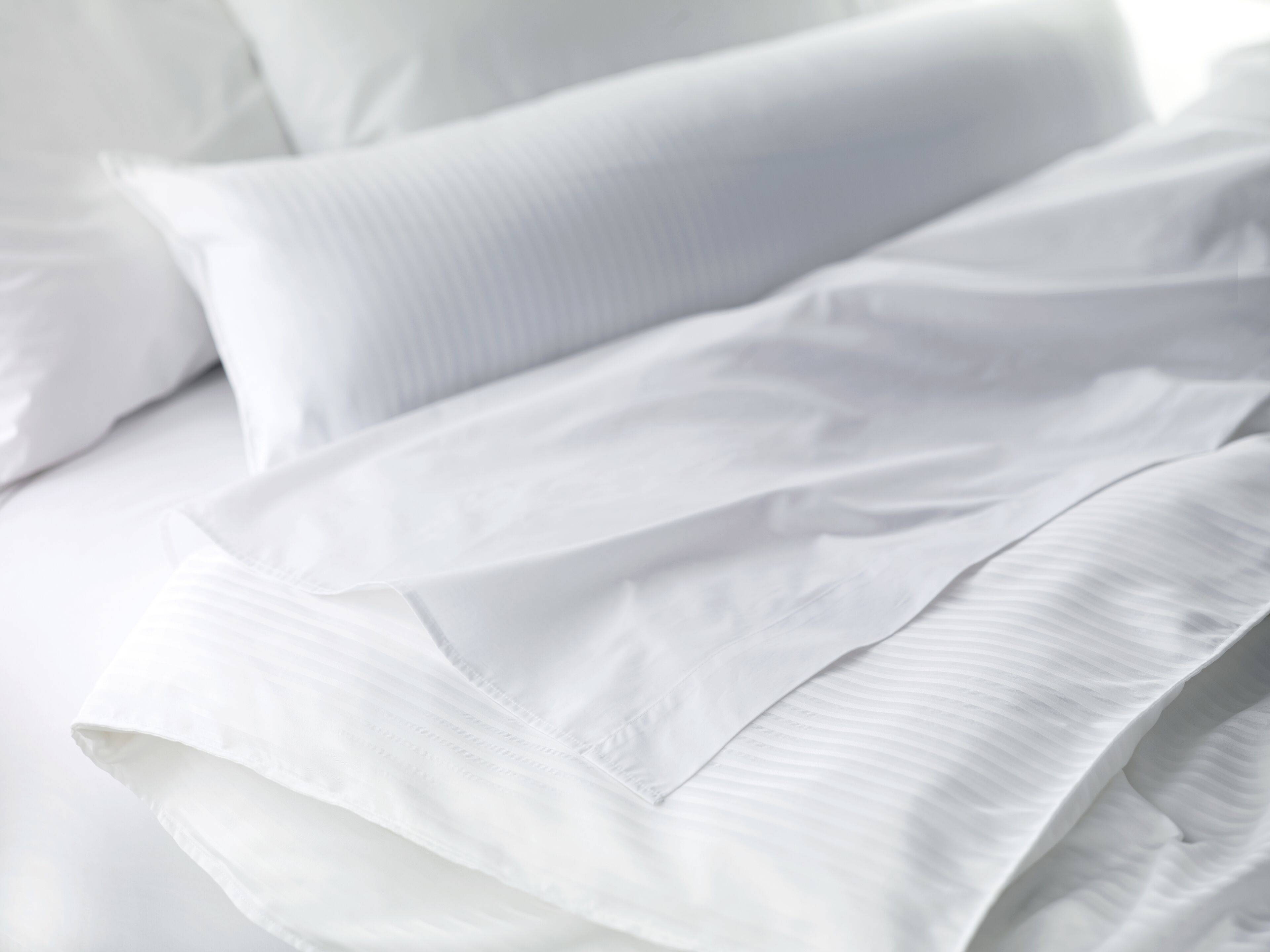 Una cama con ropa de cama y almohadas blancas.