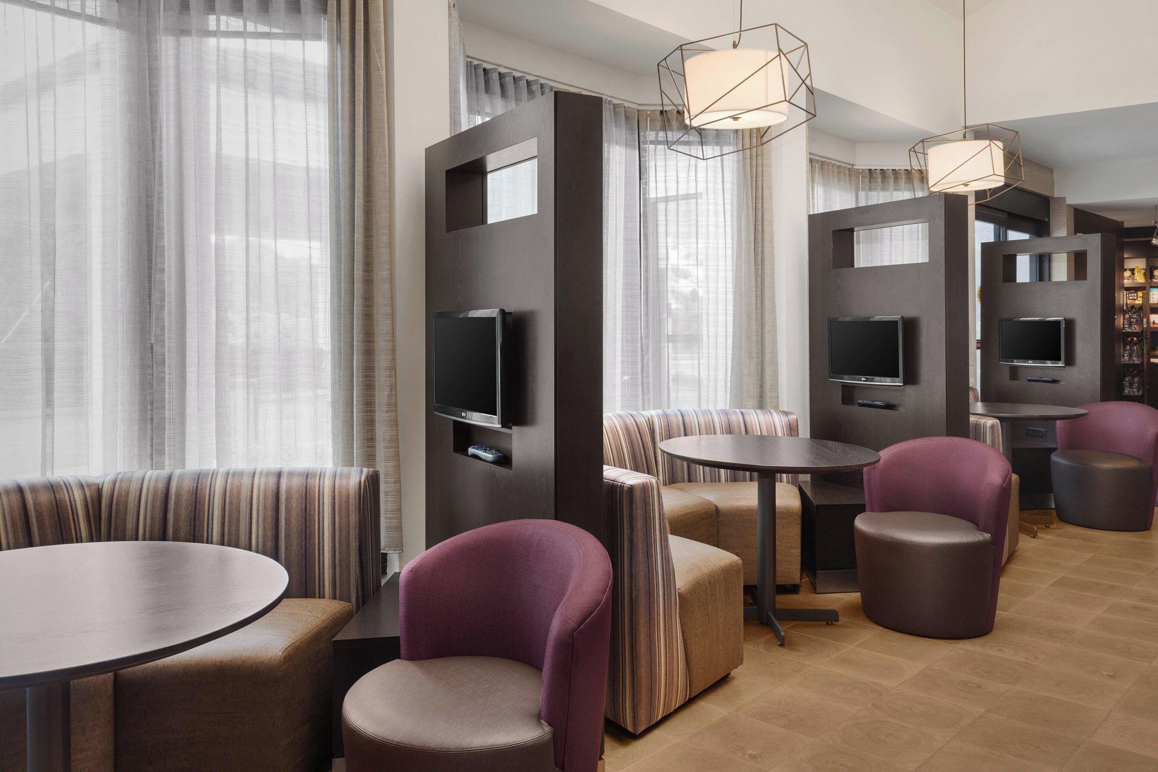 A modern lounge area with seating, tables, and televisions.