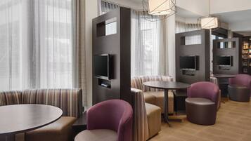 A modern lounge area with seating, tables, and televisions.