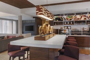 A modern bar area with a central island, seating, and a variety of food and drink displays. - Courtyard by Marriott Philadelphia Willow Grove (Willow Grove)