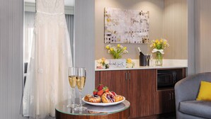 A room with a wedding dress on a hanger, a plate of pastries, and two glasses of champagne on a table. - Courtyard by Marriott Philadelphia Willow Grove (Willow Grove)