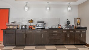 A modern kitchen with a checkered floor, wooden cabinets, a microwave, toaster, and a coffee maker. - Best Western Forsyth - Decatur (Forsyth)