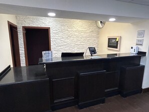 A reception desk with a stone wall backdrop, a closed door, a 'Manager On Duty' sign, and a 'Thank You For Staying With Us' sign. - Best Western Forsyth - Decatur (Forsyth)