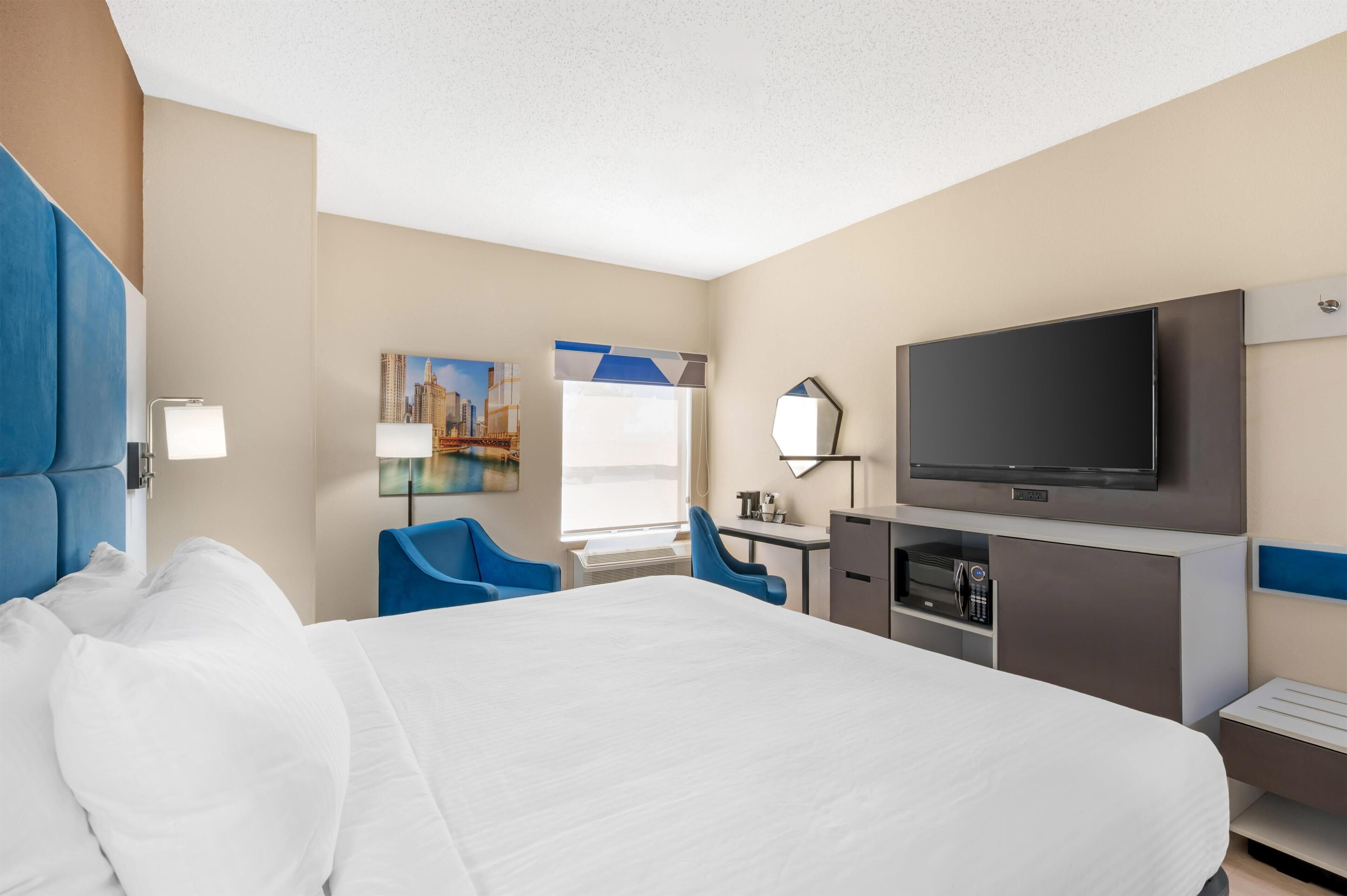 A hotel room with a bed, a desk, a television, and a chair.