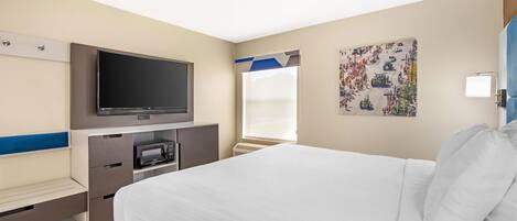 Habitación de hotel con cama, televisor de pantalla plana, microondas y ventana con persianas.
