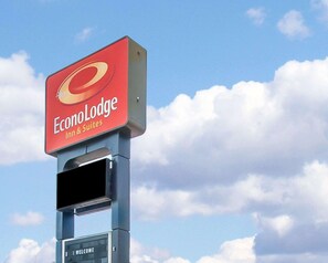 A sign for EconLodge Inn & Suites with a clear sky and clouds in the background.
