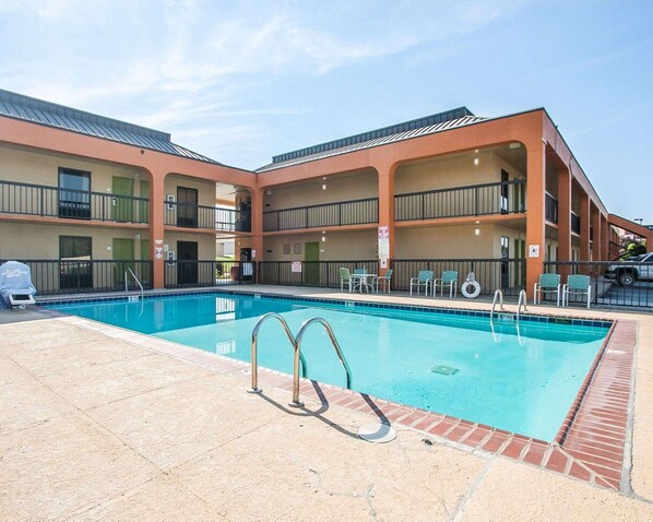 A pool area with a clear blue pool, a lifeguard chair, and a sign indicating no diving.
