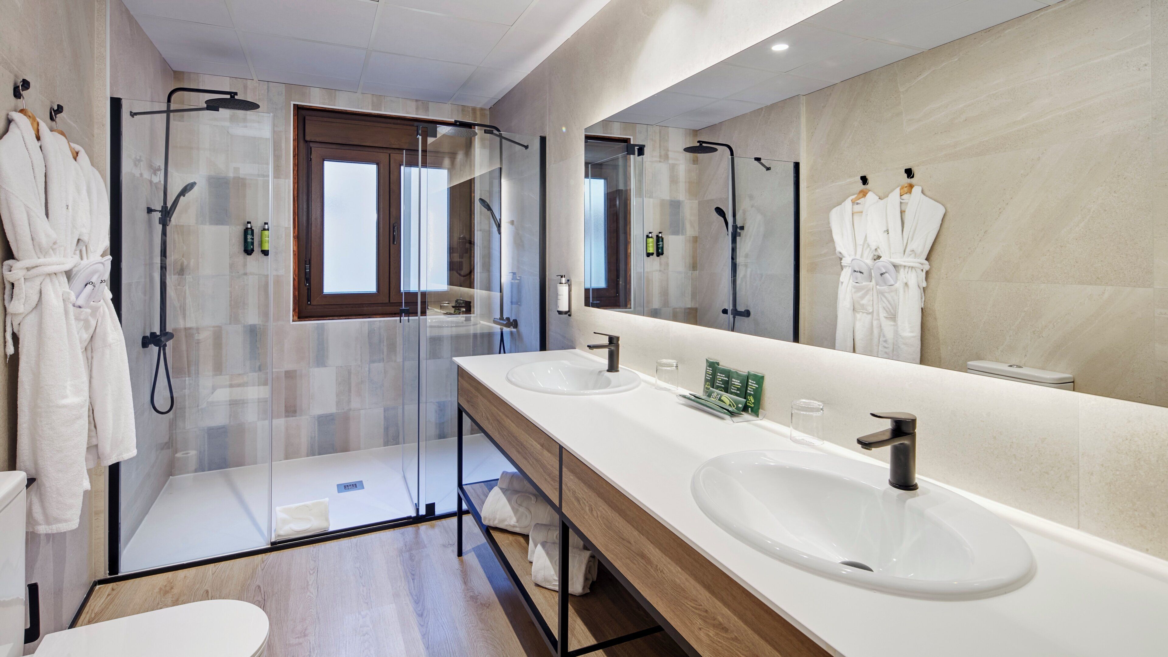 Un baño moderno con dos lavamanos, un espejo grande y una cabina de ducha de vidrio.