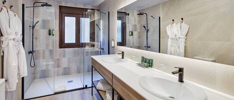 Un baño moderno con dos lavamanos, un espejo grande y una cabina de ducha de vidrio.