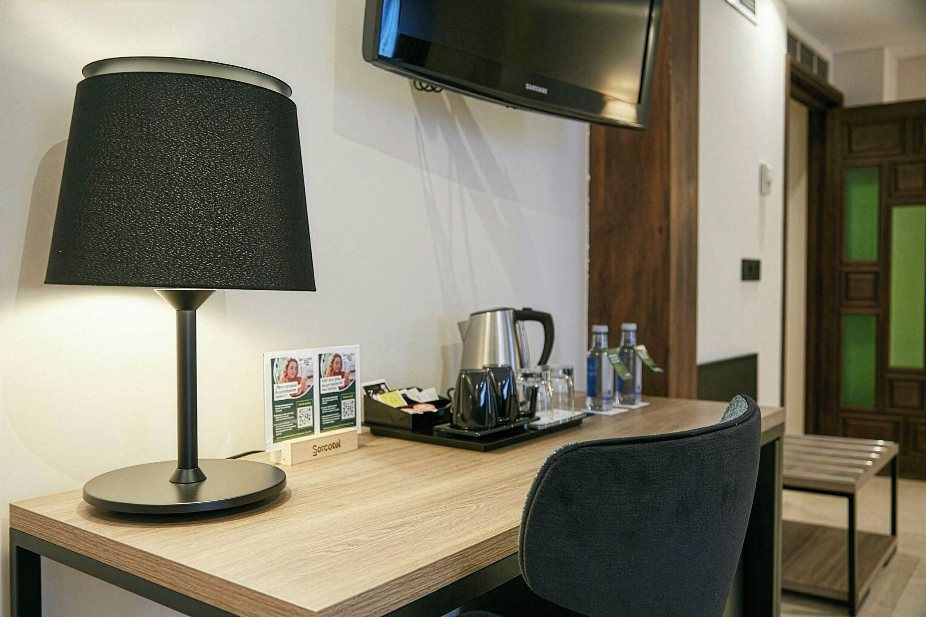 Une chambre d’hôtel équipée d’un bureau, d’une lampe, d’une télévision et d’un coin café.
