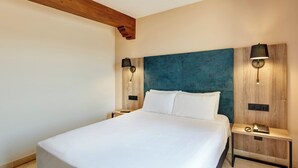 A hotel room with a large bed, two bedside tables, a wooden headboard, and wall-mounted lamps. - Hotel Sercotel Alfonso VI (Toledo)