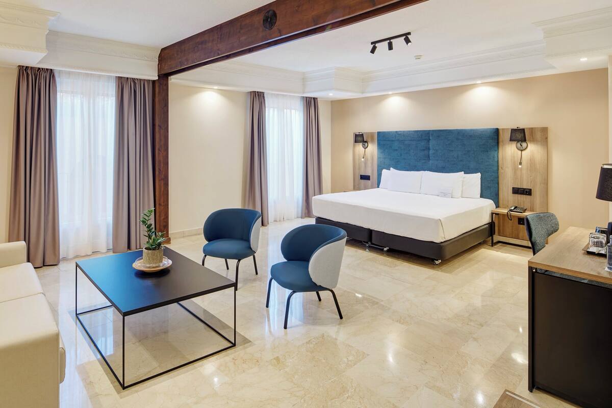 Une chambre d’hôtel moderne avec un grand lit, un bureau, une chaise et un canapé.