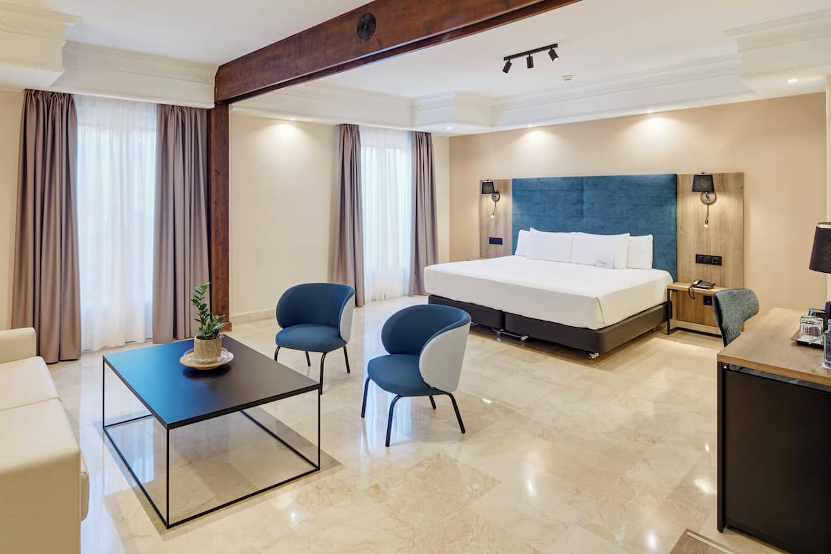 Ein modernes Hotelzimmer mit einem großen Bett, einem Schreibtisch, einem Sessel und einer Couch.