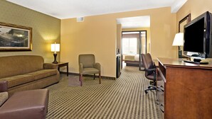 A hotel room with a sofa, armchair, desk, and television. - Days Inn by Wyndham Cheyenne (Cheyenne)