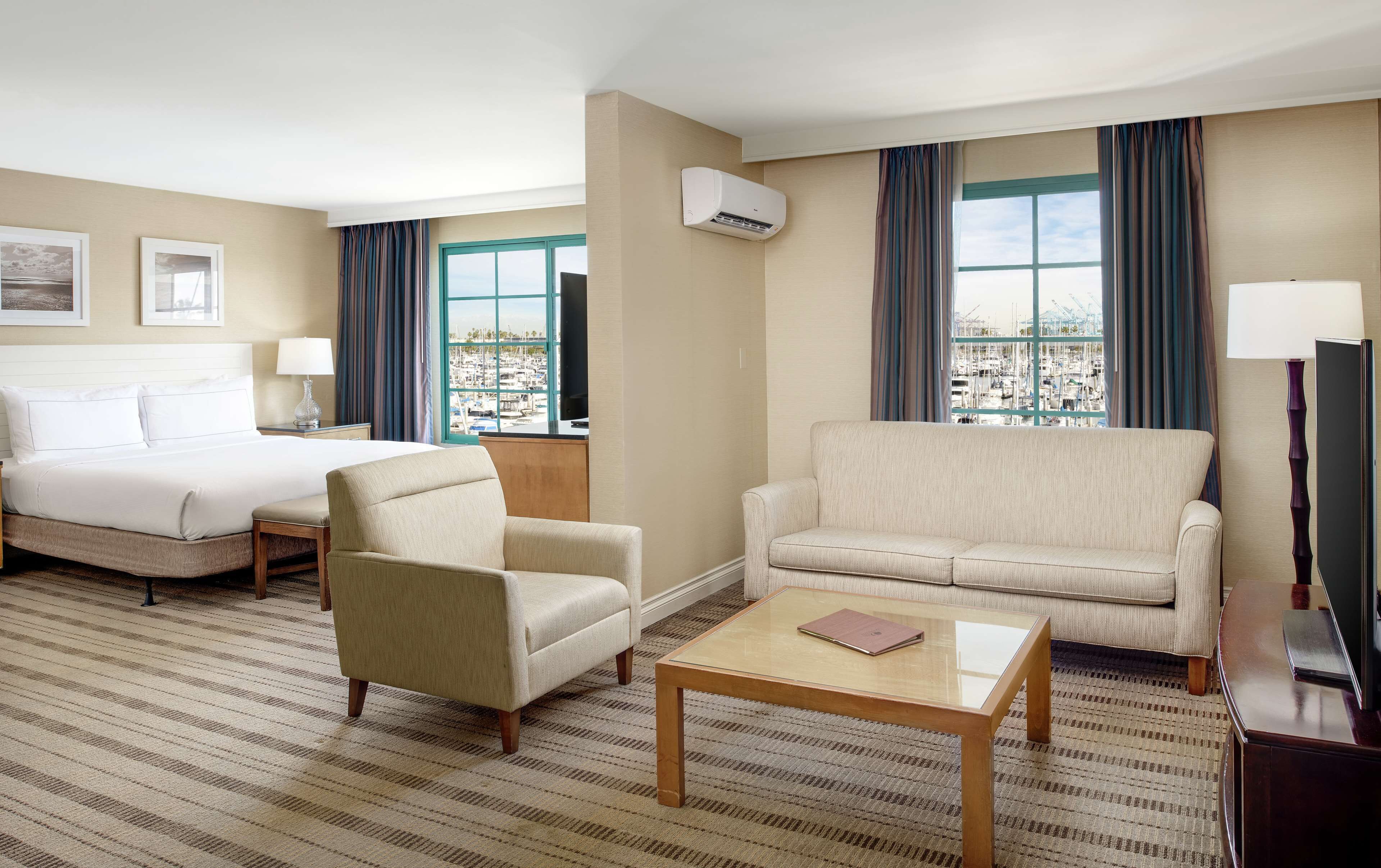 Une chambre d’hôtel comprenant un lit, deux fauteuils, un canapé, une table basse et un téléviseur.
