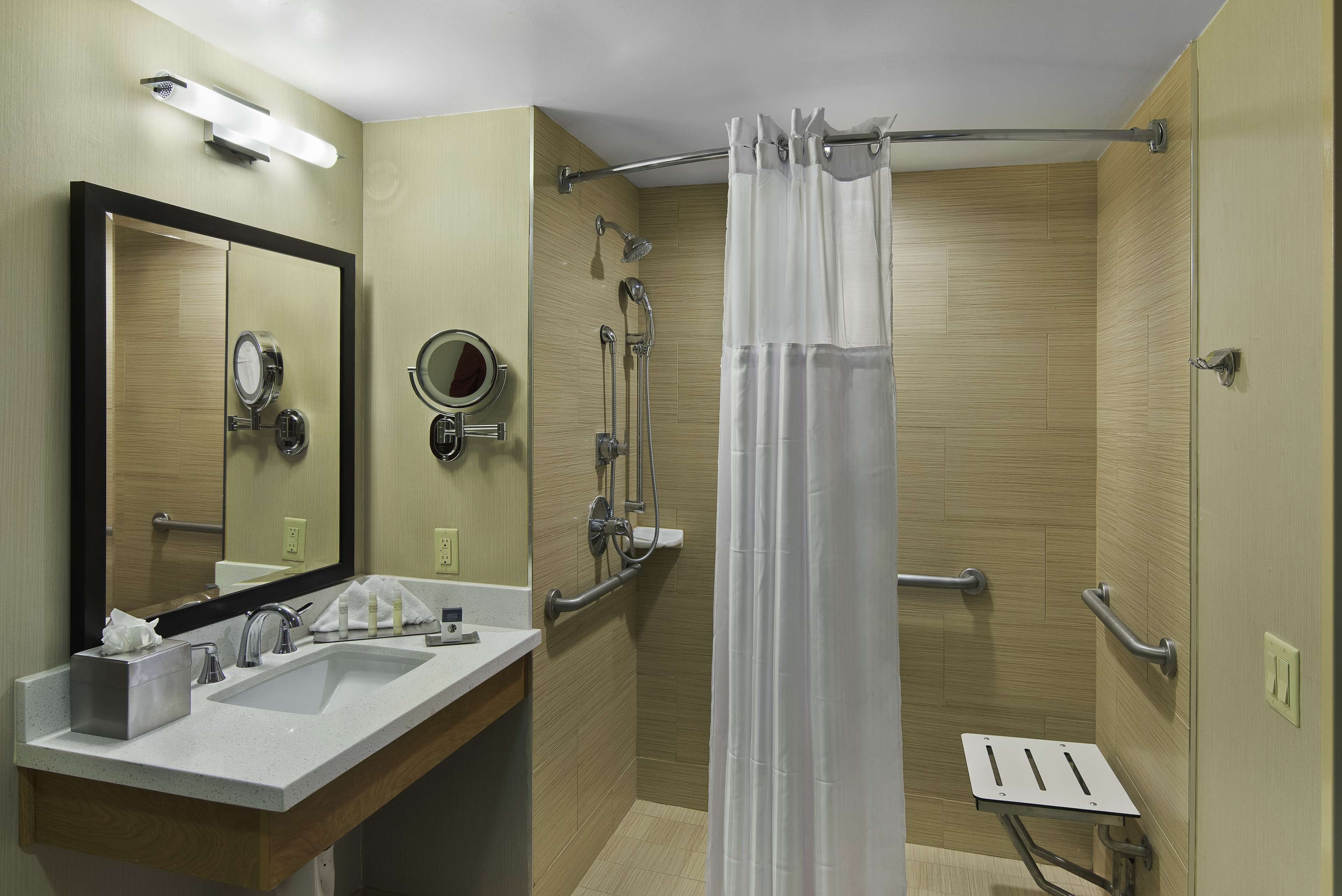 Een moderne badkamer met een wastafel, spiegel en douche.