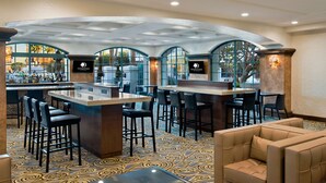 A bar area with high stools, a sofa, and a bar counter. - DoubleTree by Hilton San Pedro - Port of Los Angeles (San Pedro)