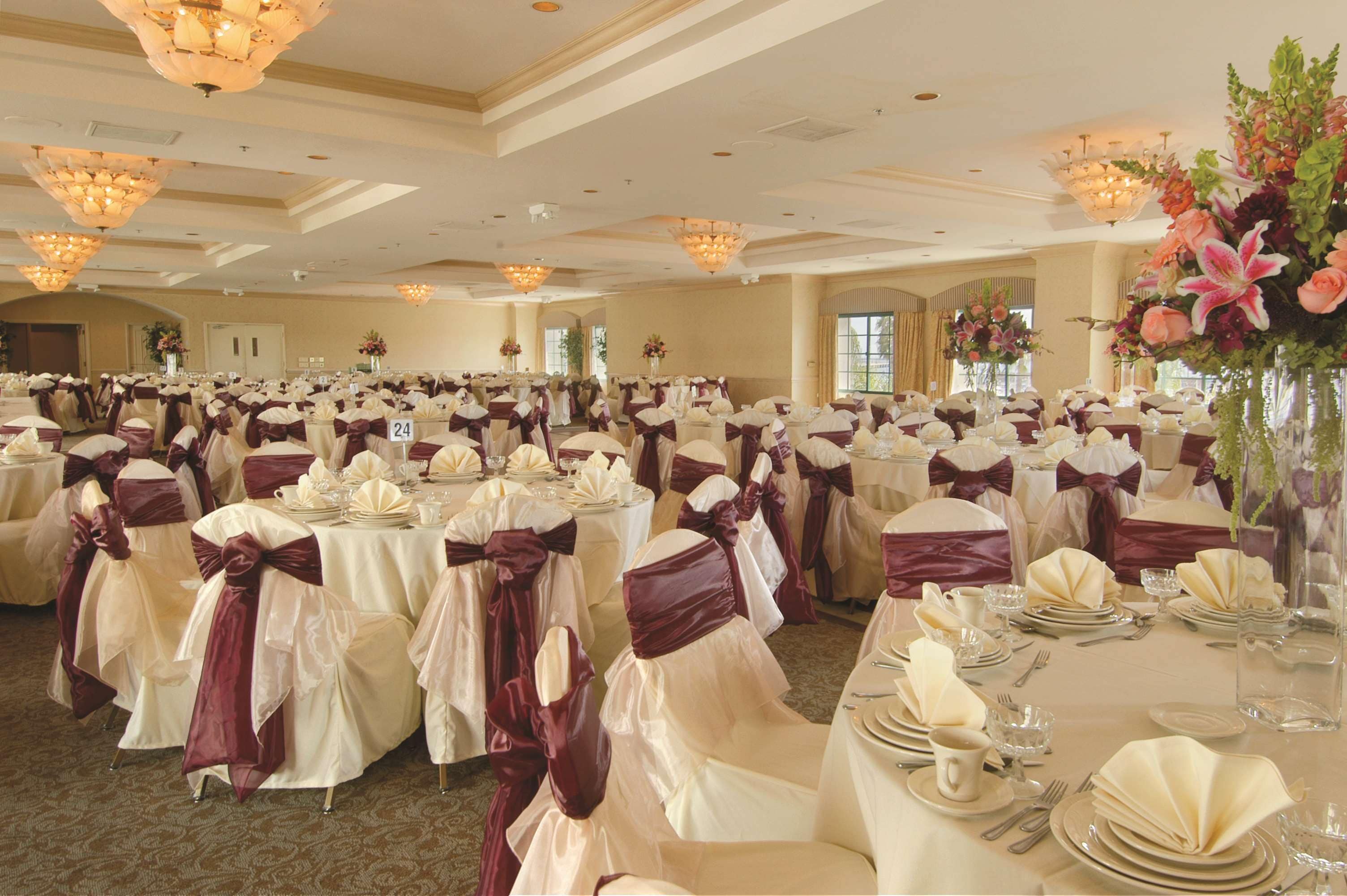A banquet hall with round tables set for a formal event, featuring white tablecloths and purple sashes.