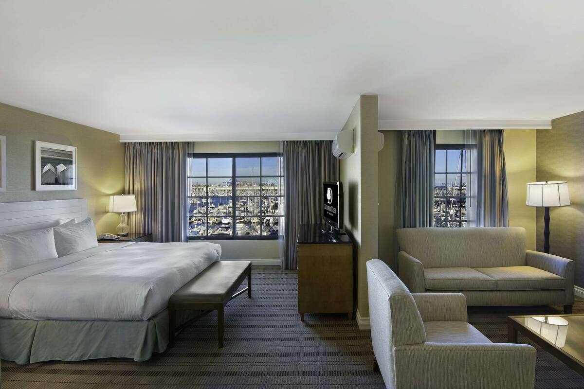 Une chambre d’hôtel avec un grand lit, un canapé, une télévision et une vue sur la ville.