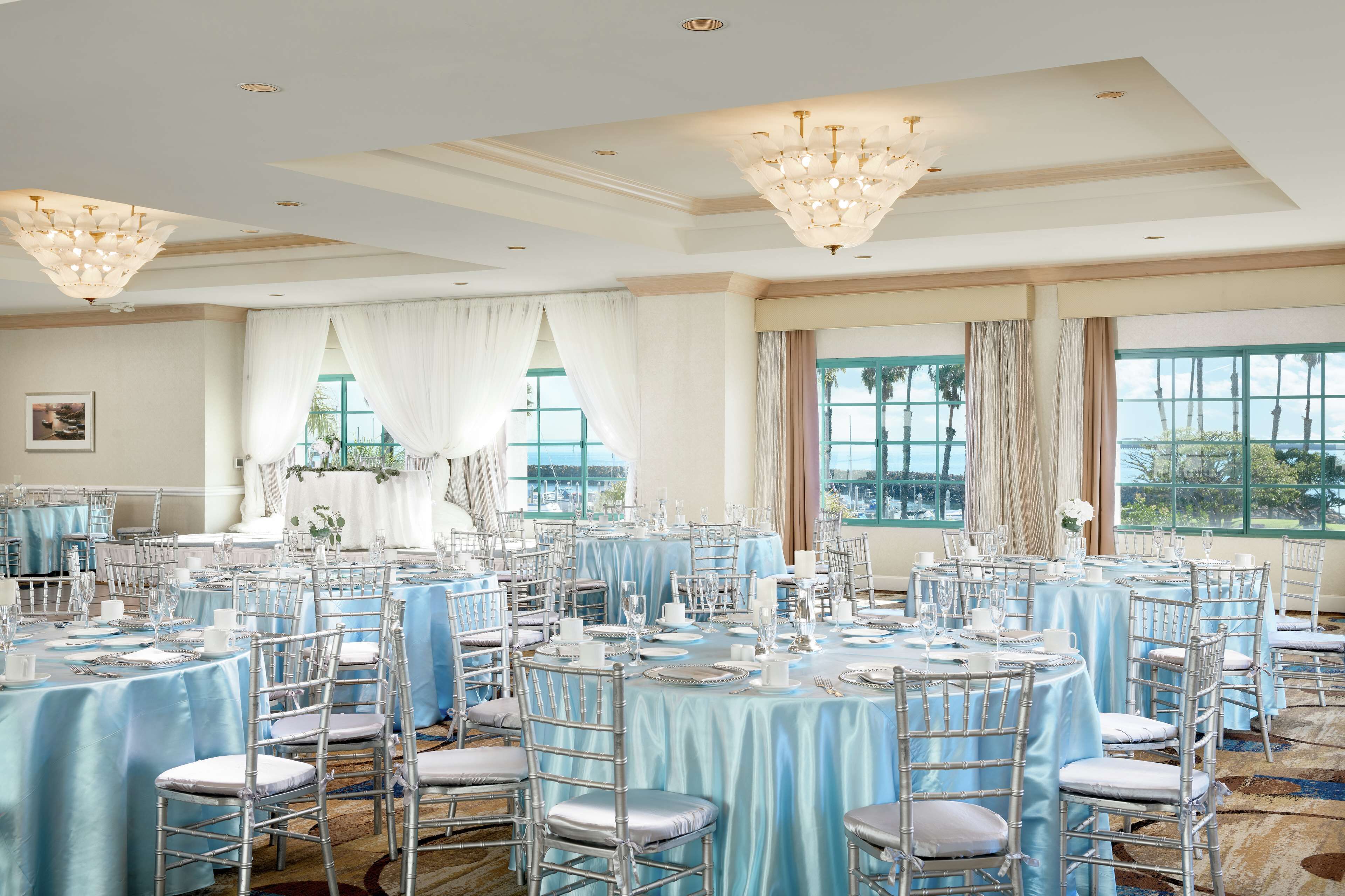 Un salón de banquetes con mesas redondas, sillas y candelabros.