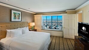 A hotel room with a large bed, a television, a window with a city view, and a door. - DoubleTree by Hilton San Pedro - Port of Los Angeles (San Pedro)