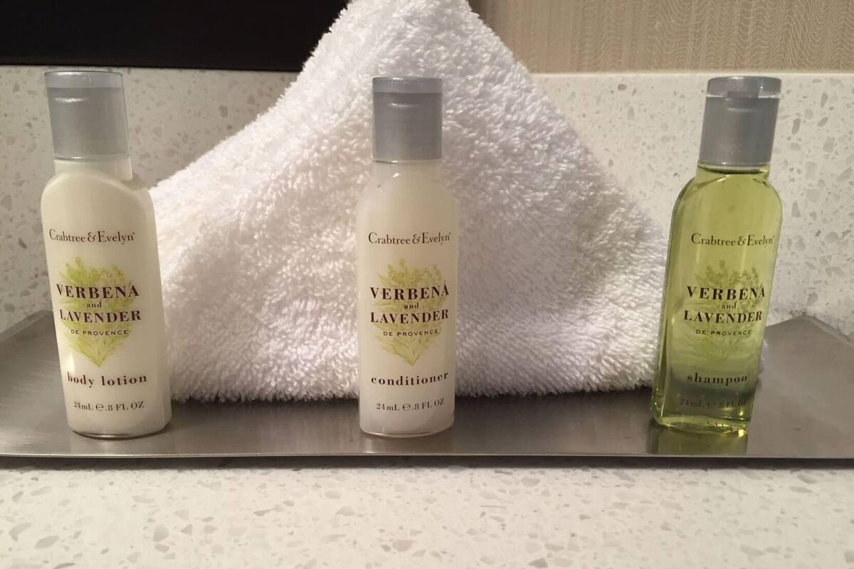Trois flacons de lotion pour le corps, d’après-shampoing et de shampoing Verbenia et Lavande de la marque Crabtree & Evelyn, posés sur un comptoir.