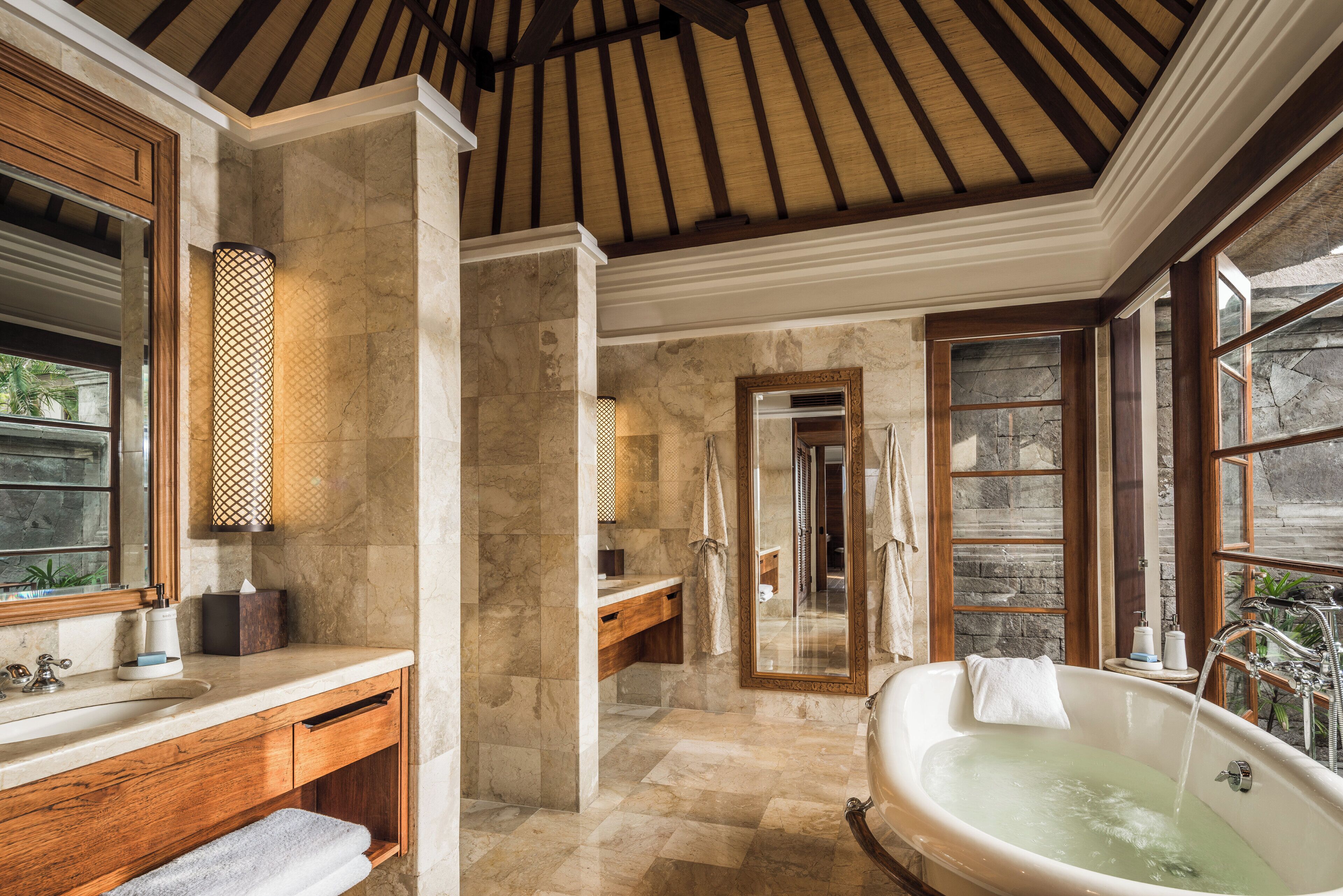 Ein geräumiges Badezimmer mit einer freistehenden Badewanne, einem großen Spiegel und einem hölzernen Waschtisch.