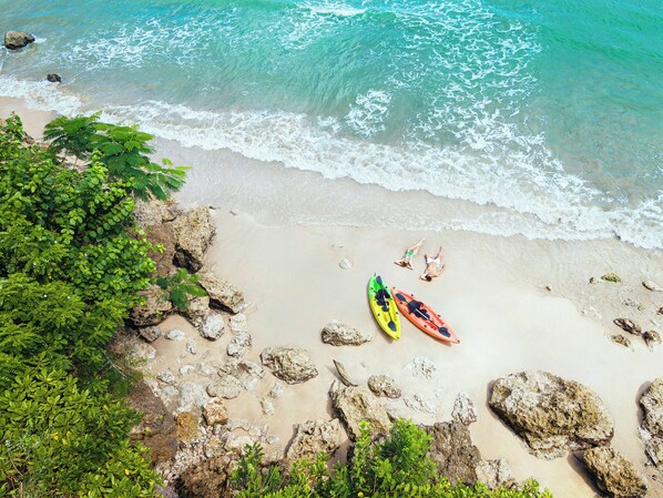 A beach with kayaks and a rocky shoreline.