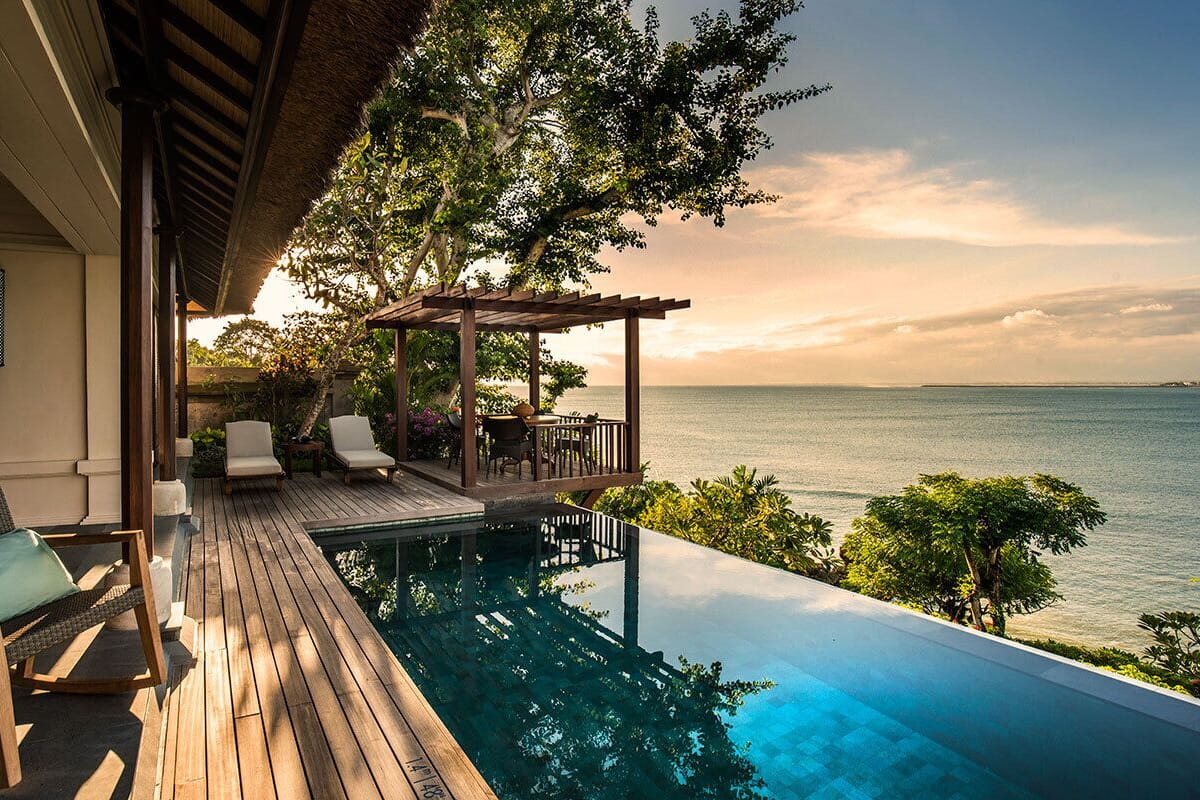 Ein Infinity-Pool mit Holzterrasse, Liegestühlen und einer Pergola mit Blick aufs Meer.
