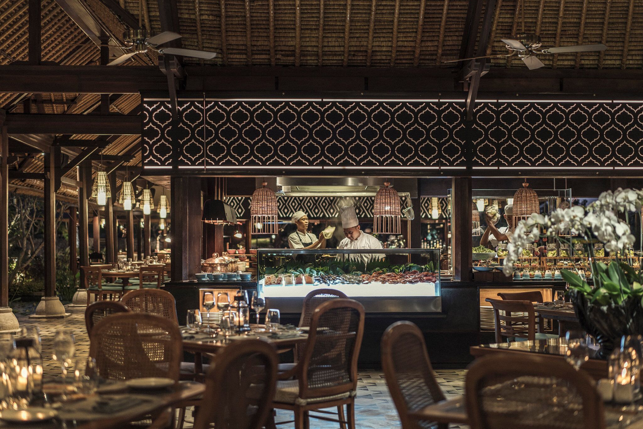 Un restaurante con mostrador central, sillas y mesas de madera dispuestas para comer.