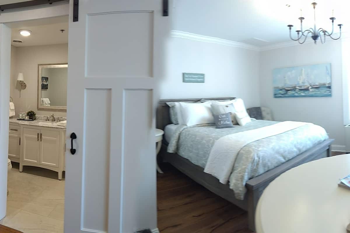 A bedroom with a bed, bedside table, and a window with a view of boats.
