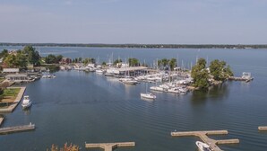 A marina with multiple boats docked, surrounded by trees and a clear sky.