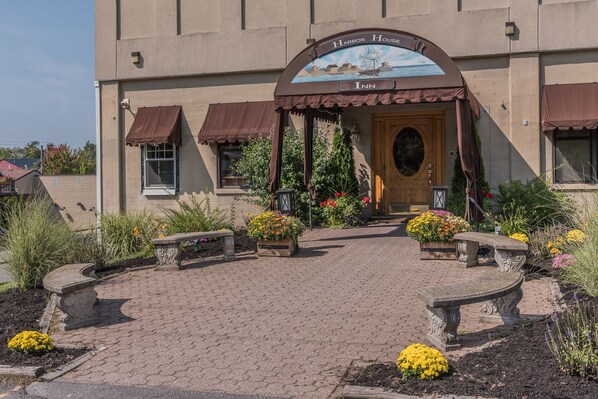 A Harbor House Inn with a nautical-themed entrance, a brick pathway, and flower beds.