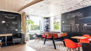 A cozy restaurant with a foosball table, blackboard menu, and bright orange chairs. - B&B Hotel Limoges 3 (Limoges)
