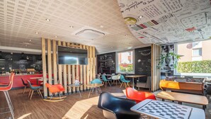 A modern cafe with a wooden ceiling, a large TV, and a foosball table. - B&B Hotel Limoges 3 (Limoges)