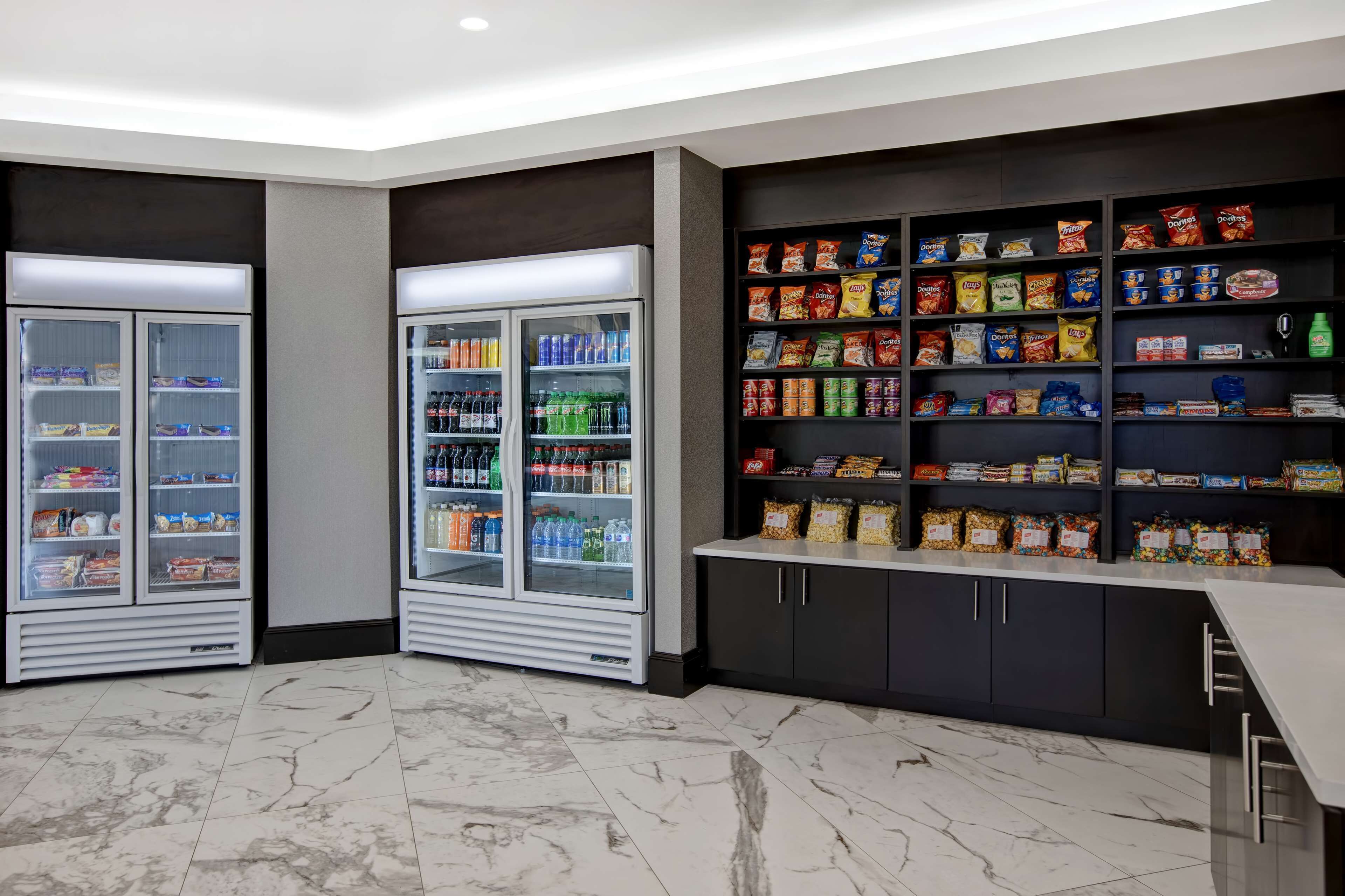 Una caffetteria ben illuminata con vetrine refrigerate e scaffali pieni di snack e bevande.