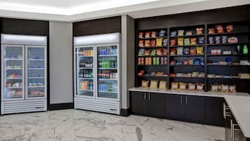 Una caffetteria ben illuminata con vetrine refrigerate e scaffali pieni di snack e bevande.
