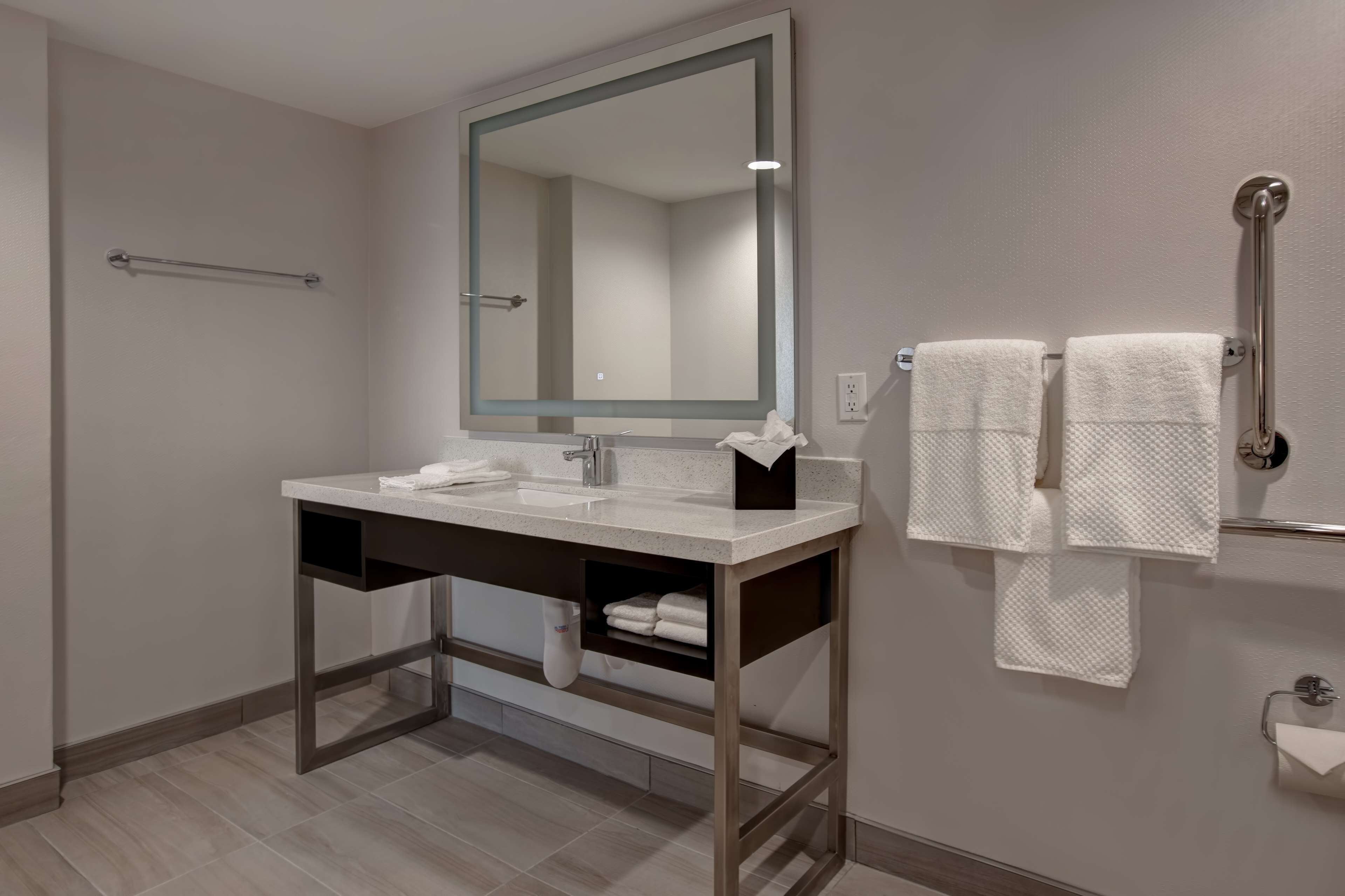 A modern bathroom with a large mirror, two sinks, and a towel rack.