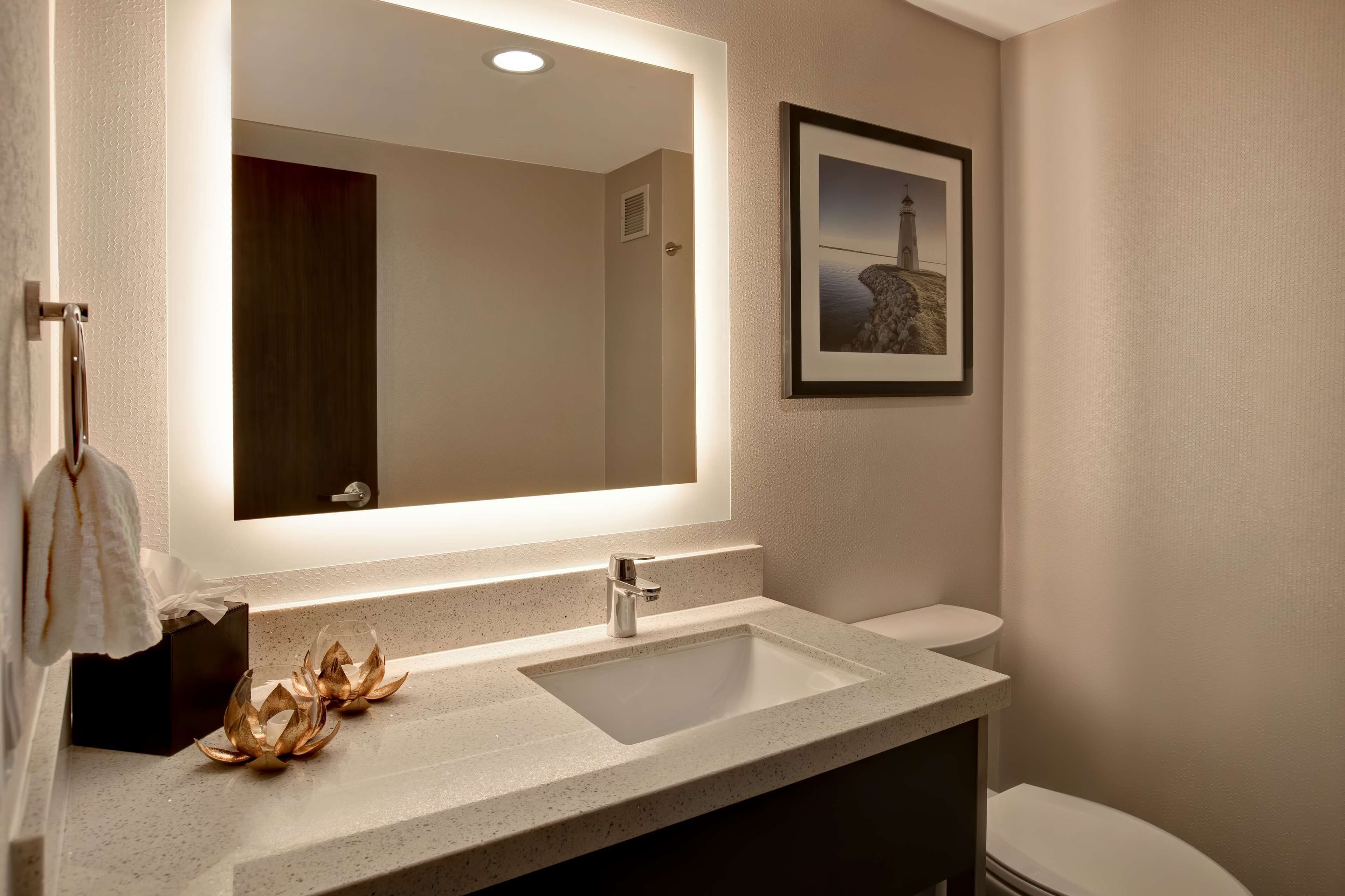 Un baño moderno con un espejo grande, un lavabo y un inodoro.