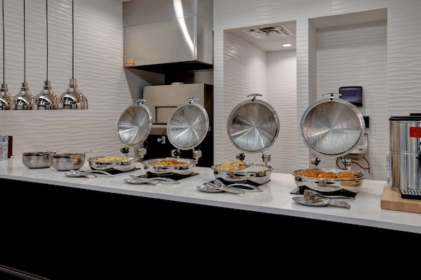 A buffet setup with various food items and a coffee machine. - Embassy Suites by Hilton Oklahoma City Northwest (Oklahoma City)