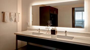 A modern bathroom with two sinks, a large mirror, and a dark cabinet.