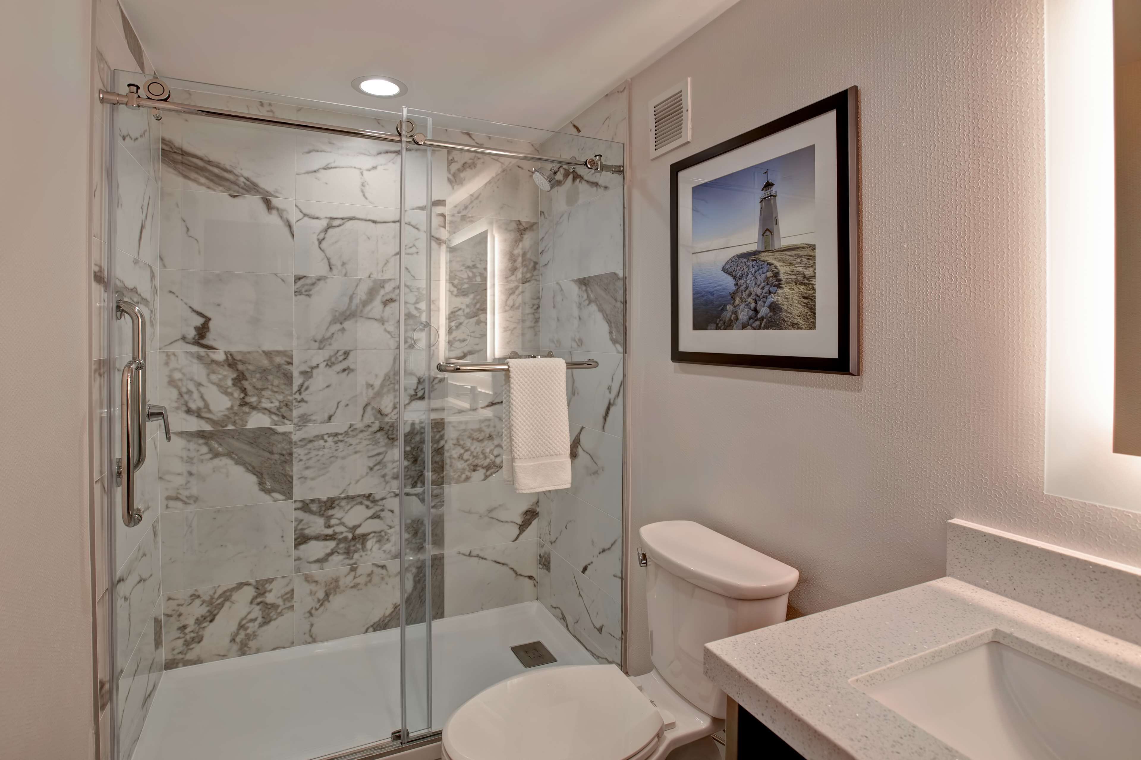 A bathroom with a glass-enclosed shower, a toilet, and a sink.