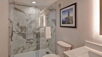 A bathroom with a glass-enclosed shower, a toilet, and a sink.