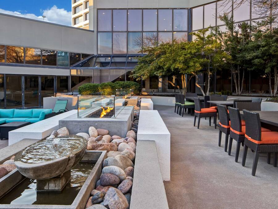 An outdoor patio area with seating arrangements, a fire feature, and a water element.