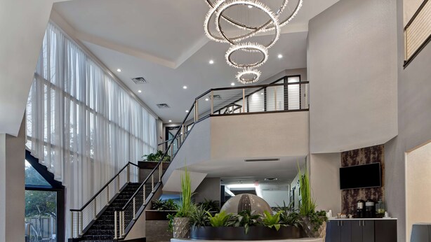 A spacious lobby with a central seating area, a staircase, and a large window providing natural light. - Embassy Suites by Hilton Oklahoma City Northwest (Oklahoma City)