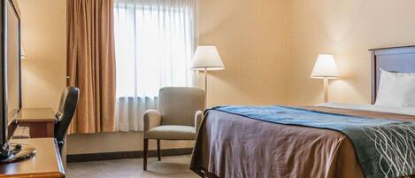 A hotel room with a bed, two bedside lamps, a desk with a chair, a window with curtains, and a lamp on the desk.